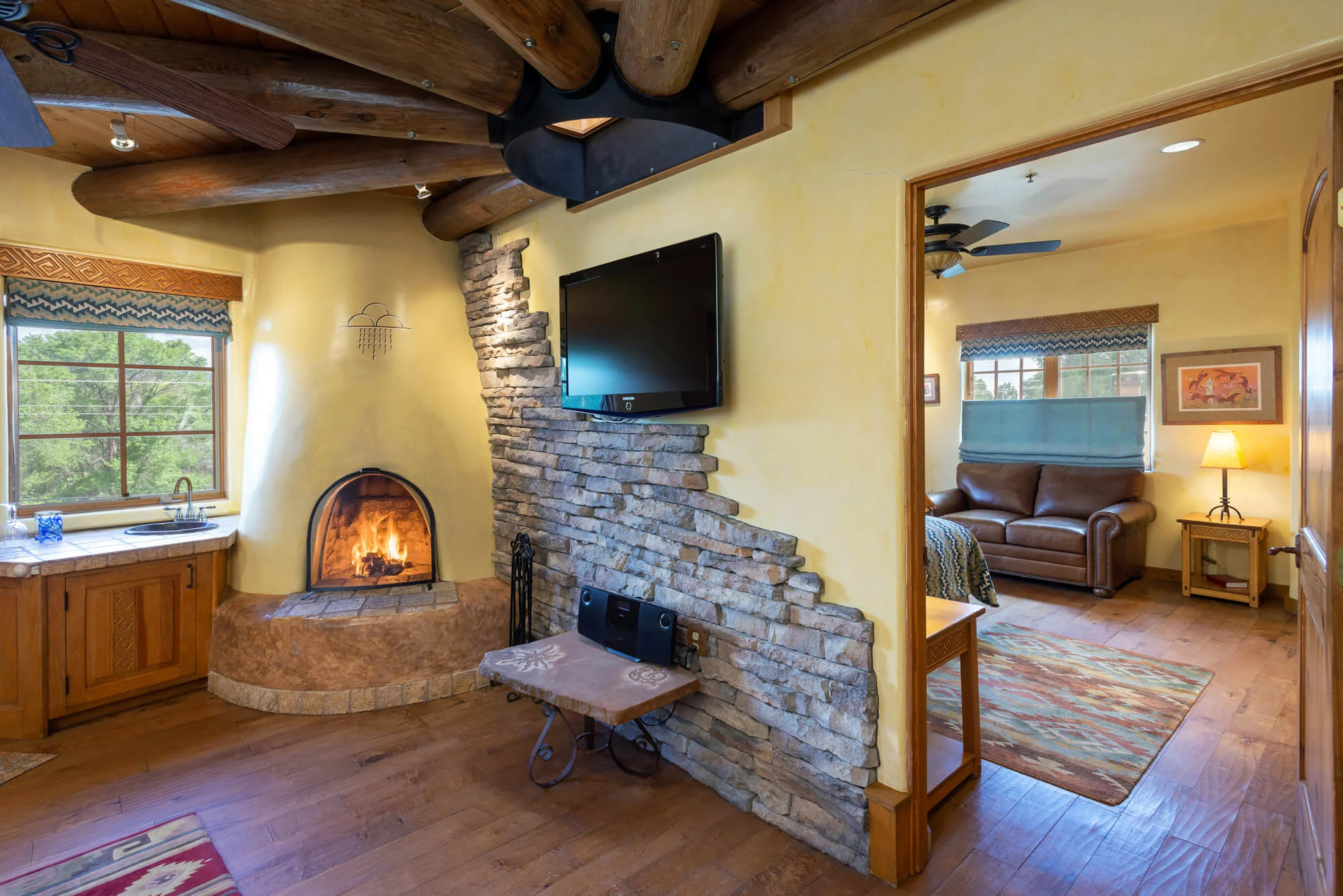 Viewing doorway to private bedroom. Main room has television and kiva fireplace next to a wet bar