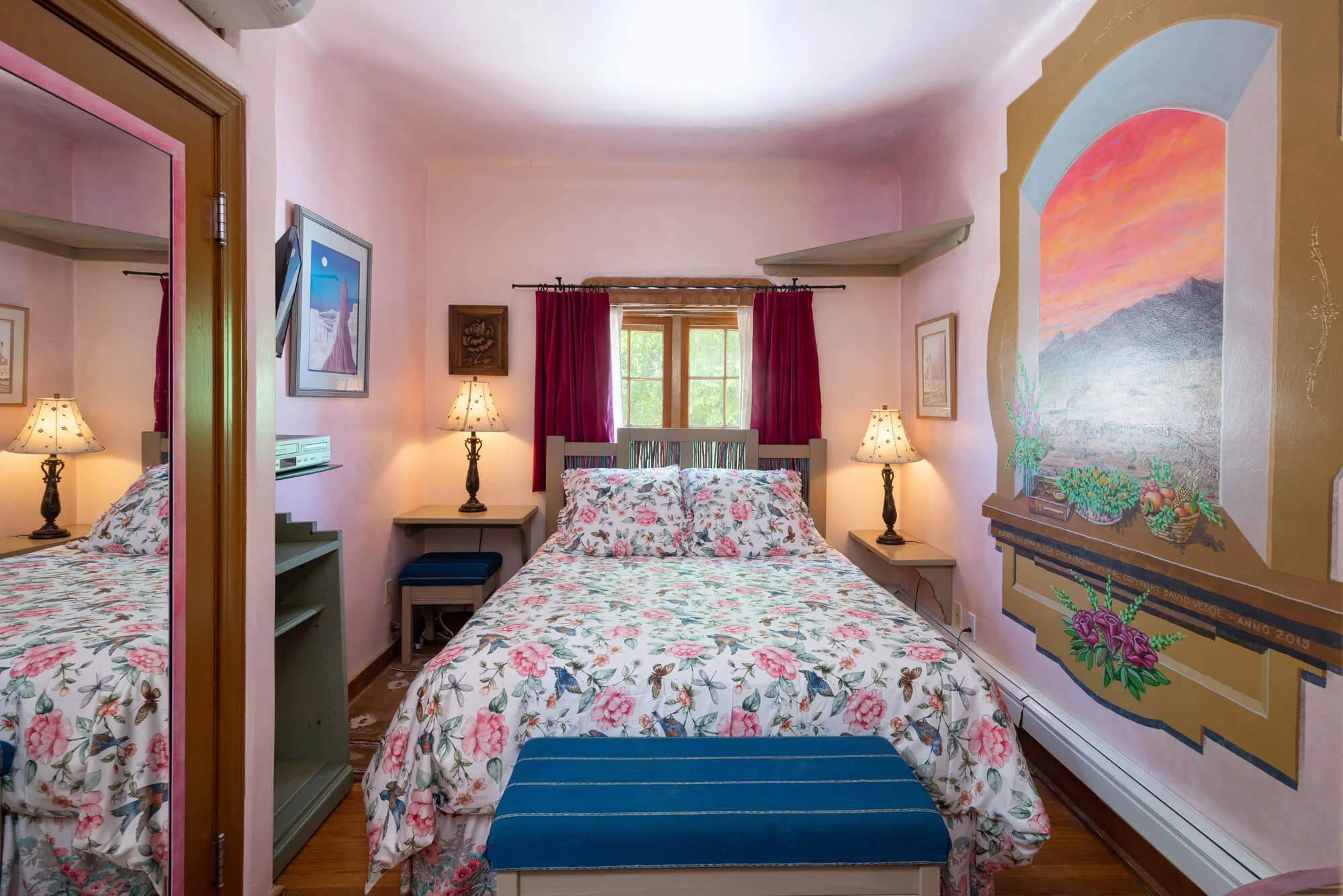 Queen bed with floral comforter and mural on the wall